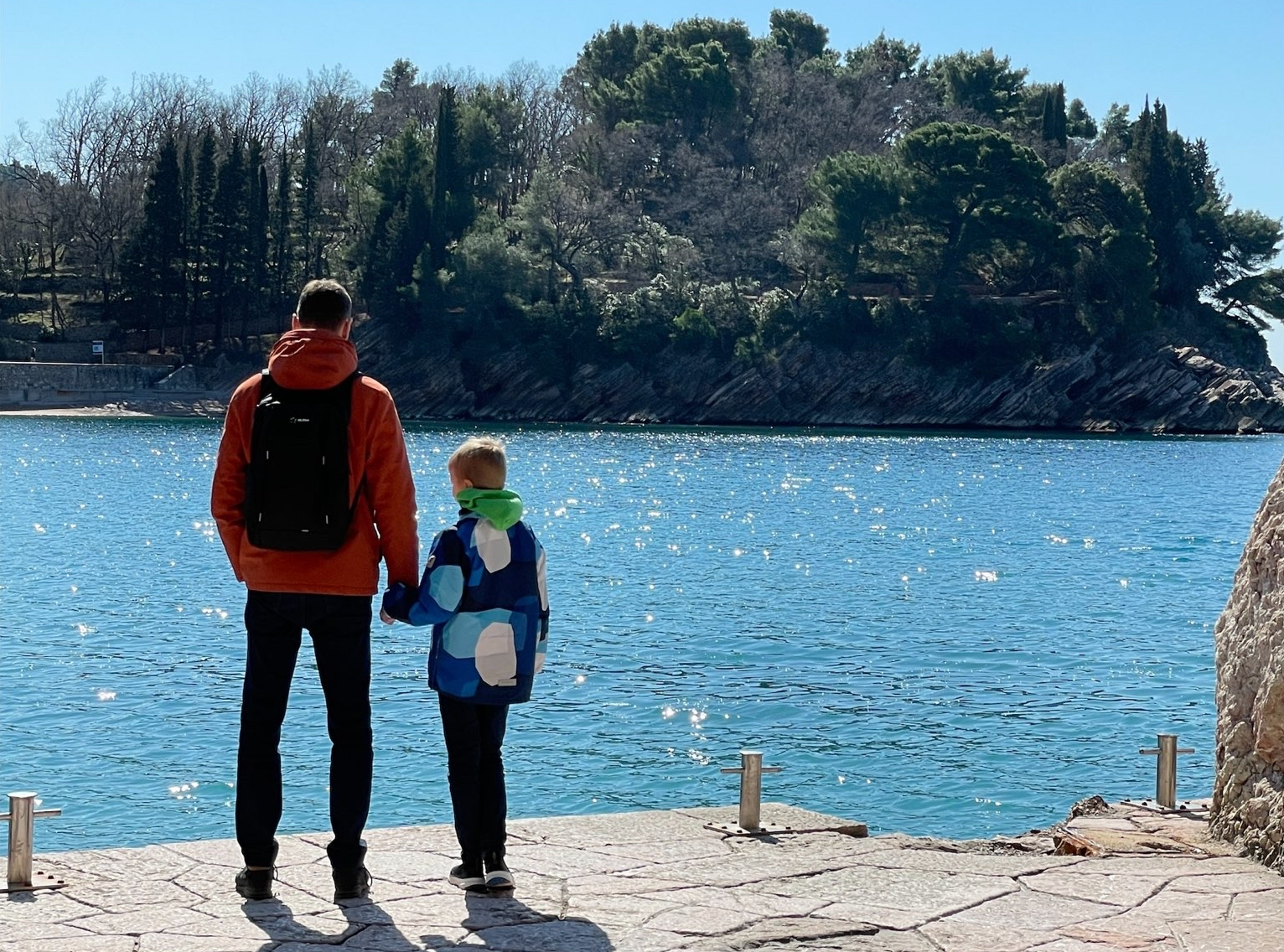 Man standing near the water with child.